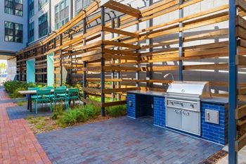 A patio with a barbecue grill and a table with chairs